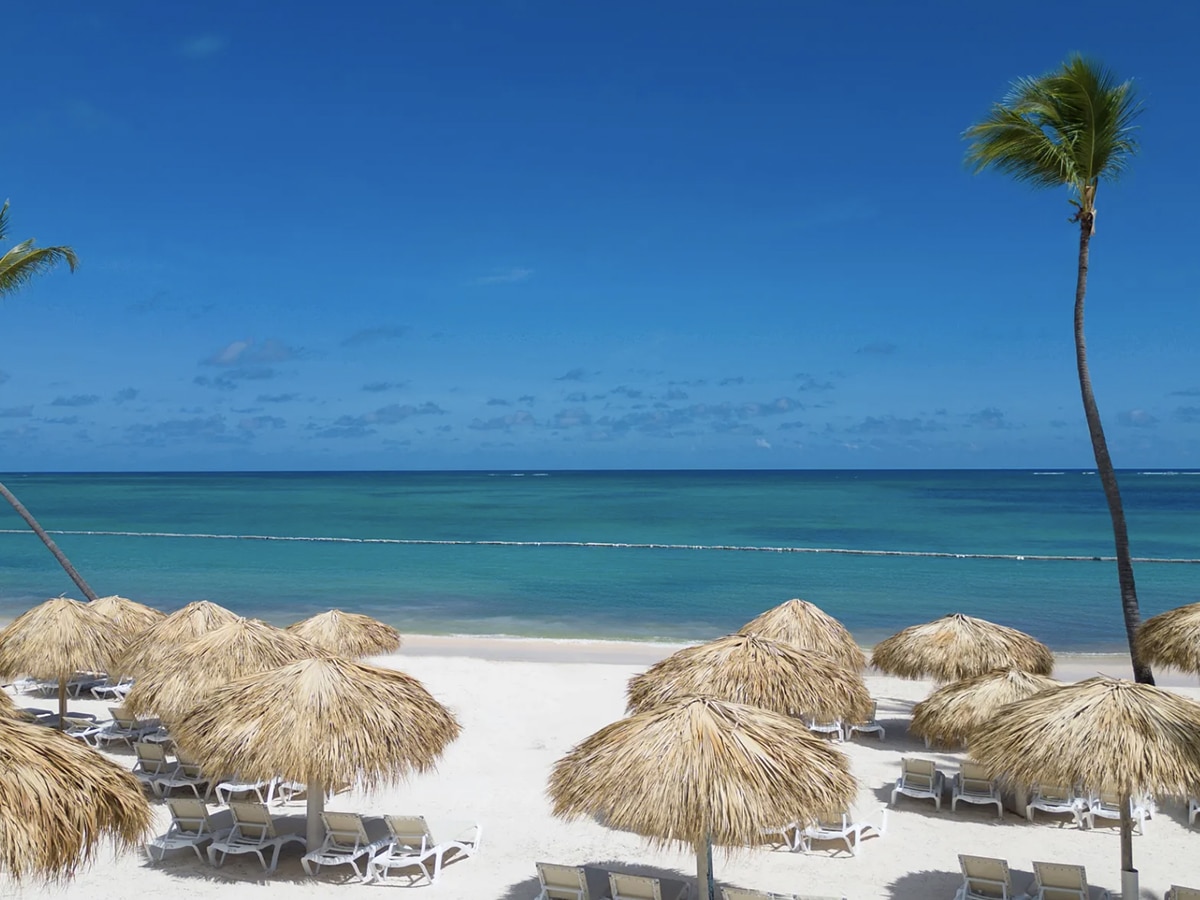 palapas on the beach with white sand and blue water