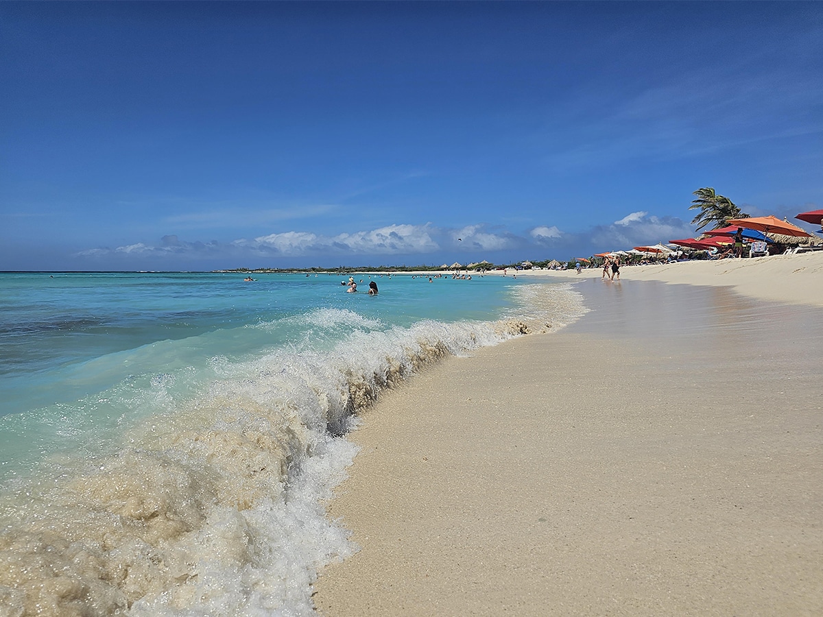 arashi beach in aruba with palapas in the background