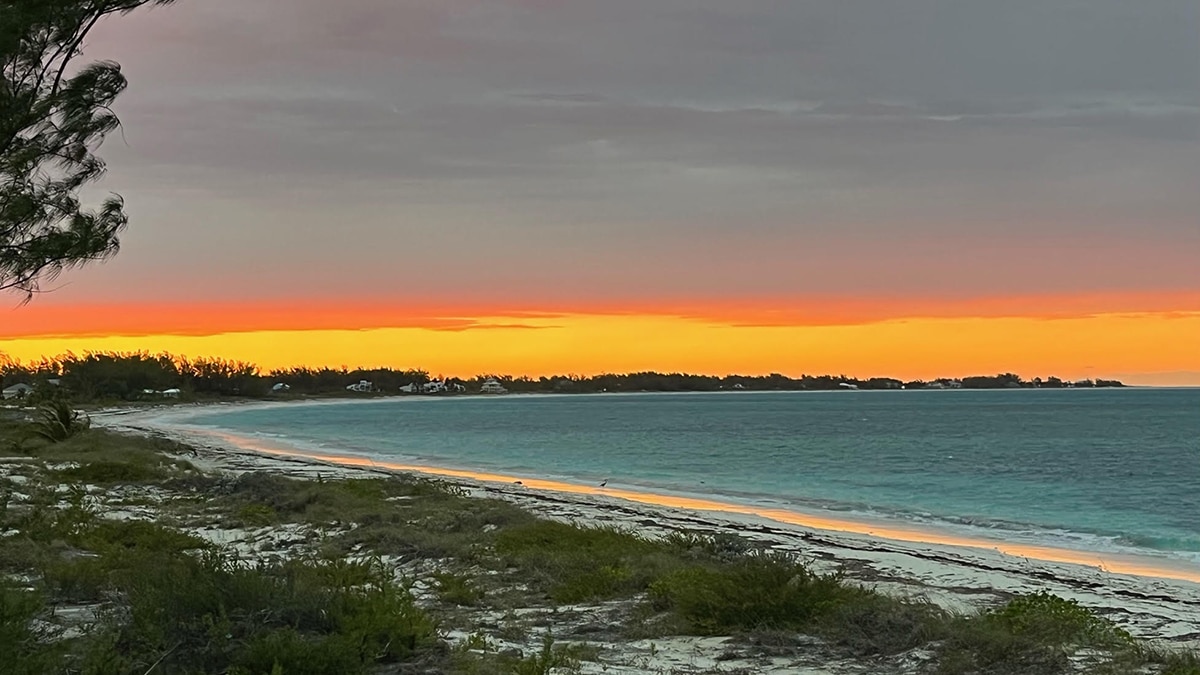 beach on great harbour cay at sunset with blue water