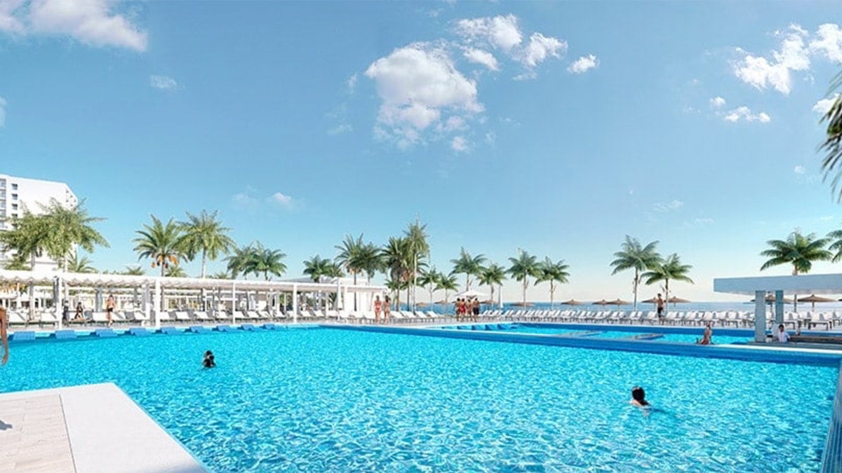 main pool at resort with palm trees and clouds in sky