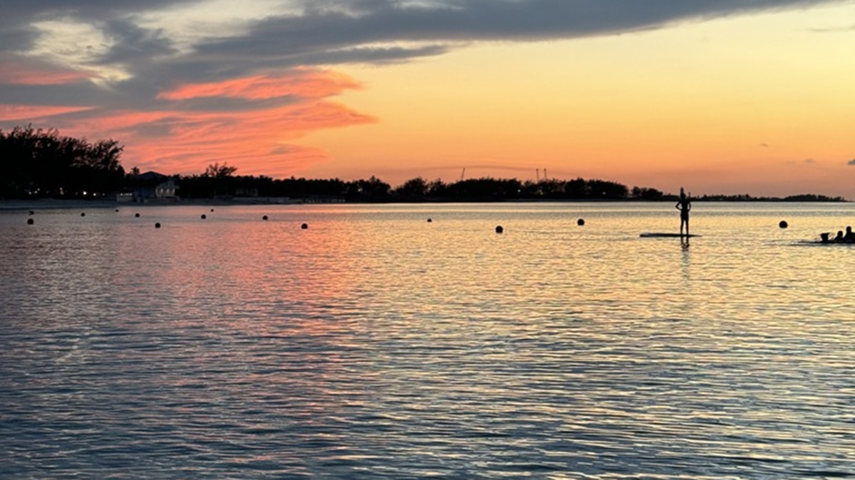 a paddleboarder at sunset on paradise island